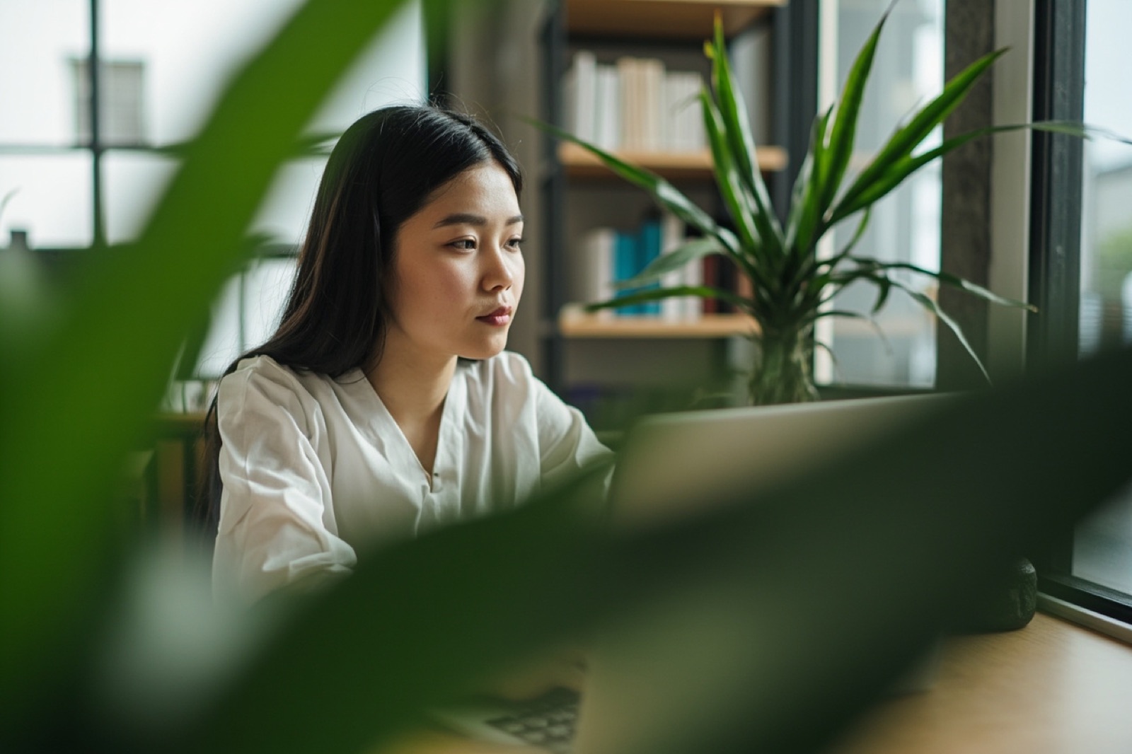 A professional working at a laptop surrounded by plants